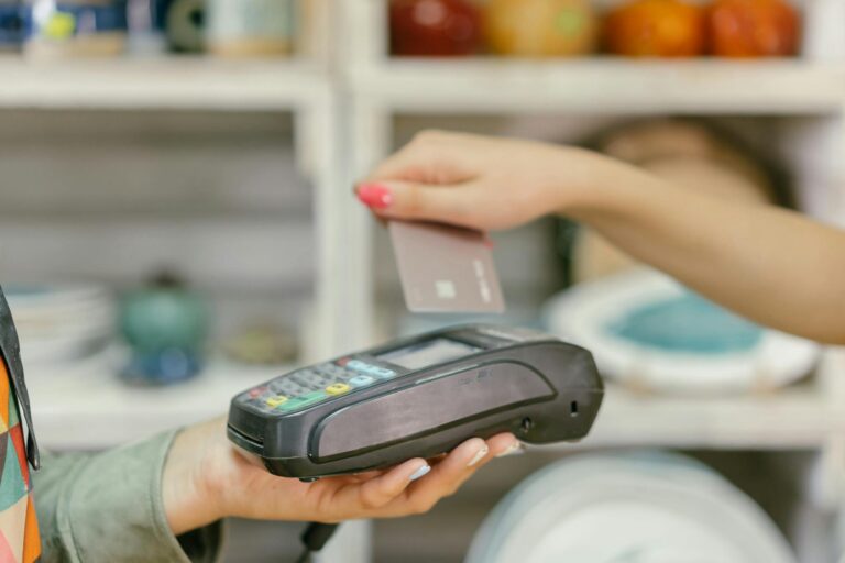 A hand using a credit card for payment at a point of sale terminal, close-up view.